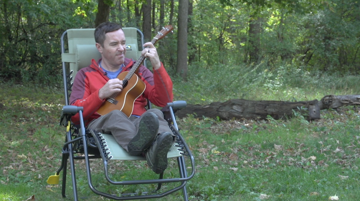 playing ukulele in a camping chair