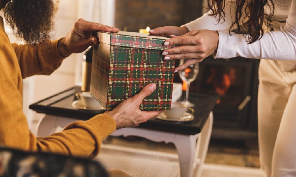 Close up shot of man opening a present his girlfriend is giving to him Close up shot of man opening a present his girlfriend is giving to him