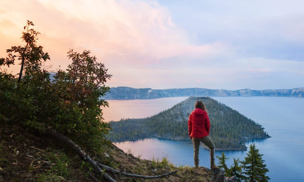 Rear view of woman standing on cliff against Crater Lake