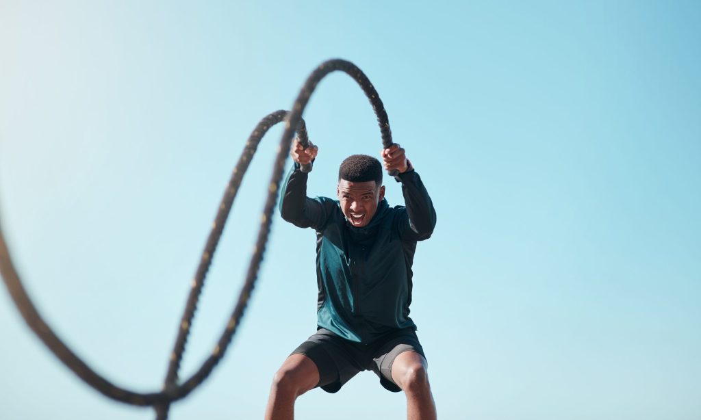 Cropped shot of a handsome young man using battle ropes during a high intensity workout outdoors