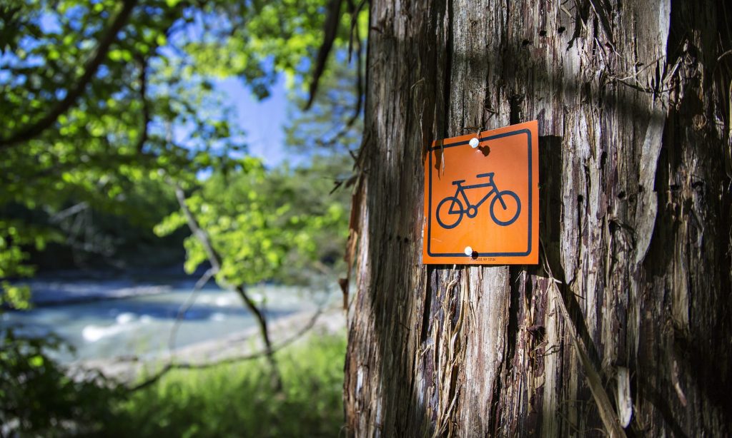 mountain biking signage on a mountain bike trail in Northwest Arkansas with a orange sign nailed to a tree in nature