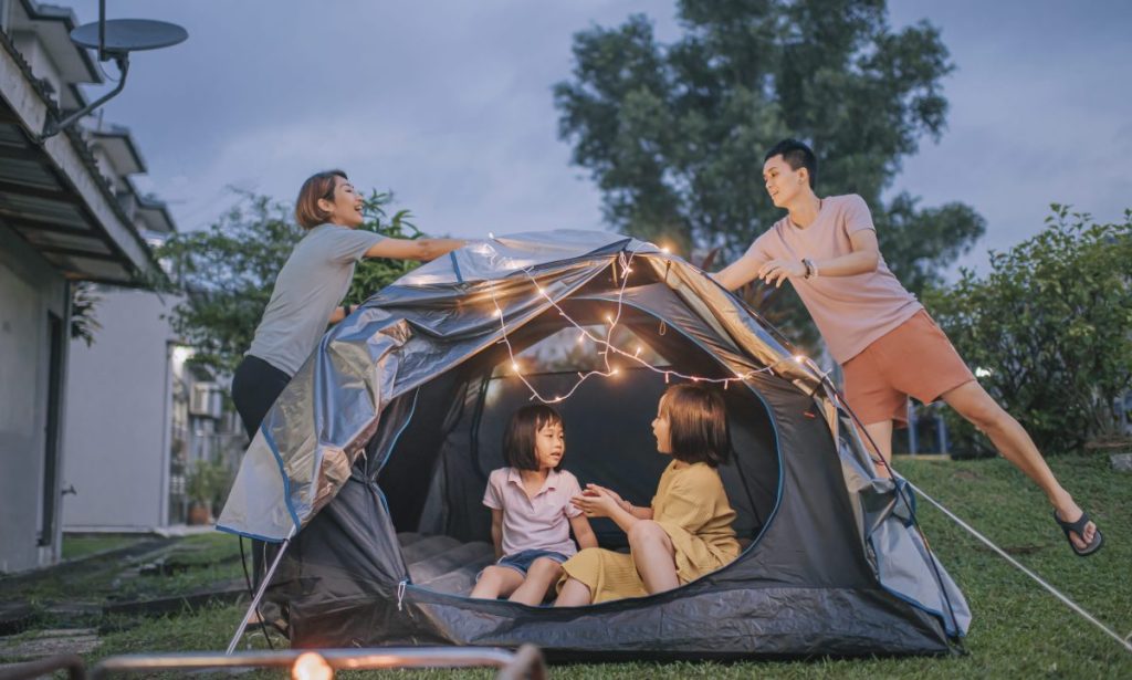 Asian chinese family putting on string light decorating camping at backyard of their house staycation weekend activities
