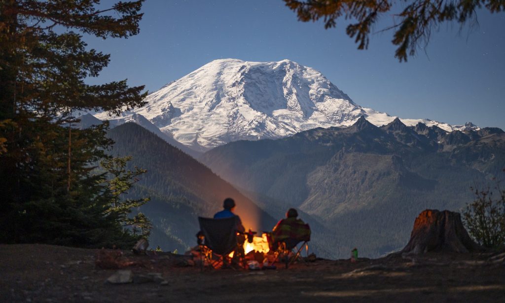 Silhouetted campers around the fire with Mount Rainier behind