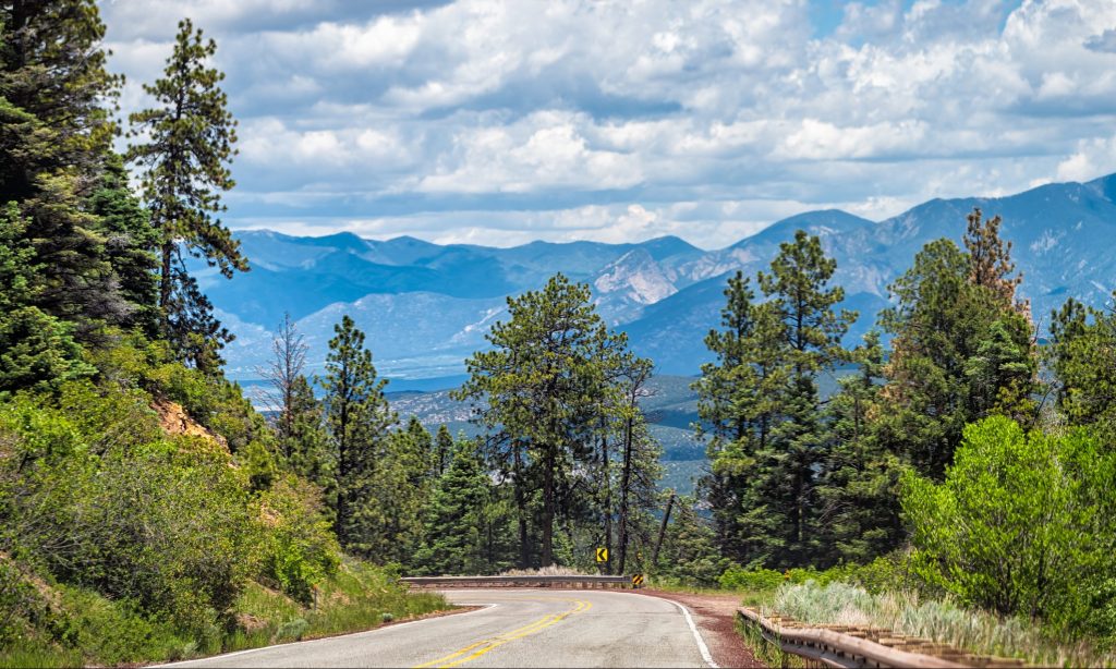 Carson National Forest highway 76 with Sangre de Cristo mountains in background with green pine tree forest in summer at high road to Taos