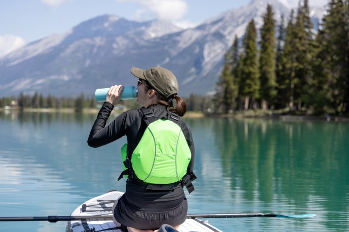 Woman on a paddle board drinking out of a water bottle