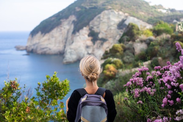 Woman hiking on coastal footpath, looking at the sea